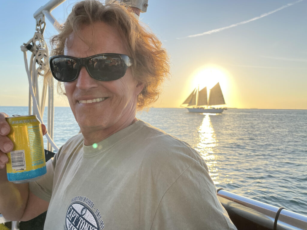 Tom sits on a boat at sunset.